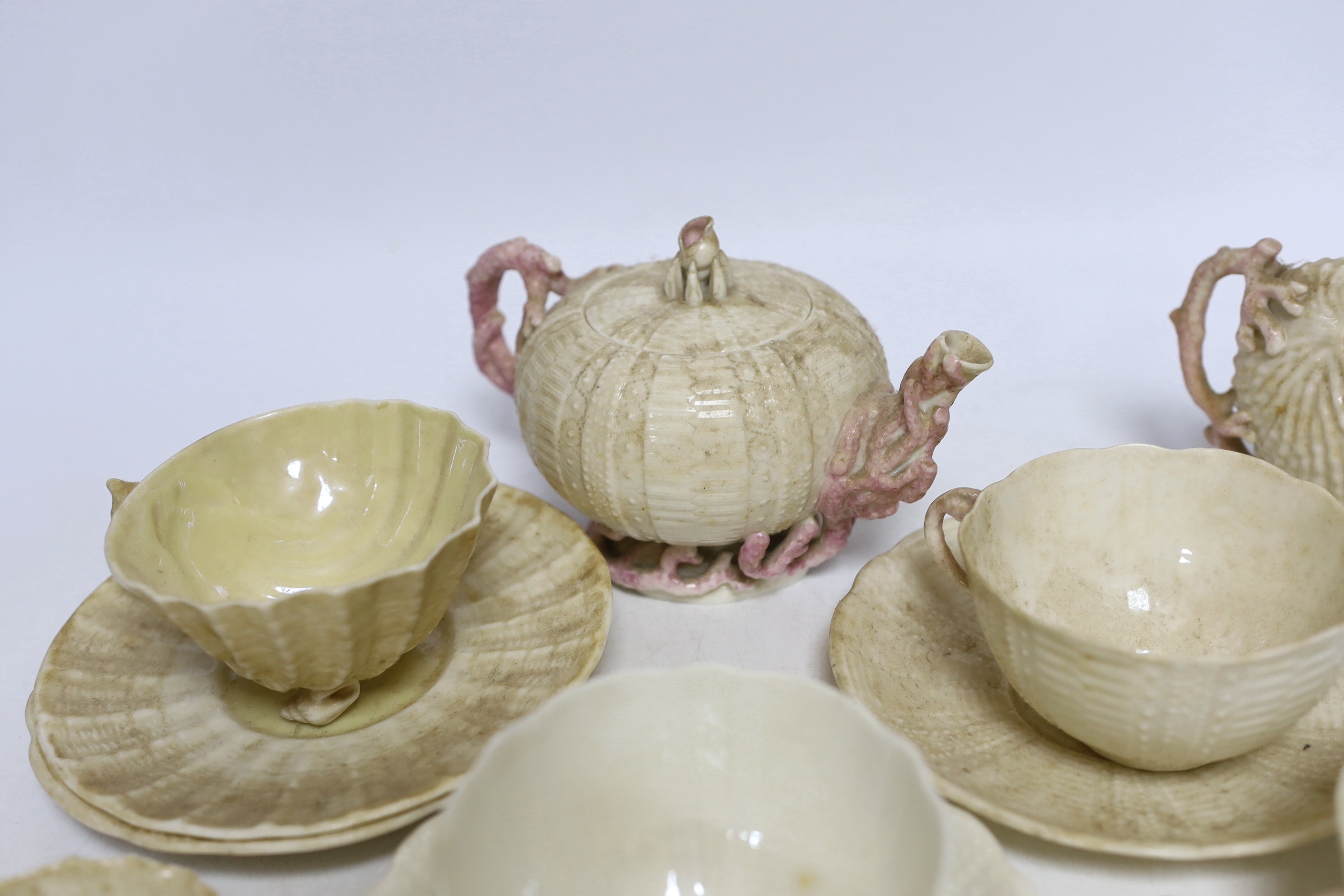 A quantity of Belleek including a teapot, three cups and saucers and a shell design vase, mostly first period